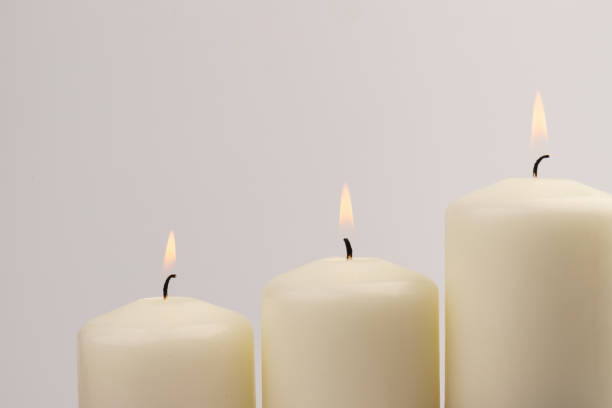 istock Burning white wax candles on white background. 1437216212