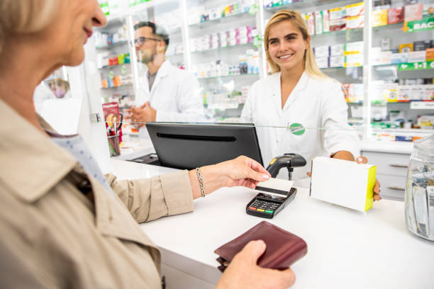 клиент оплачивает лекарства фармацевту в аптечном магазине с помощью кредитной карты. - note pad medicine healthcare and medicine pharmacy стоковые фото и изображения
