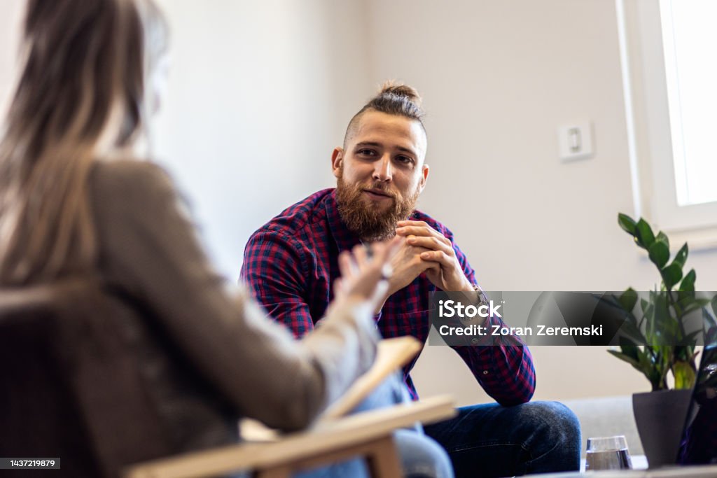 Female psychologist talking to young man during session. Mental Health Stock Photo