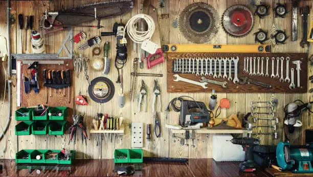 Photo of Various tools hang on a wooden wall in a workshop