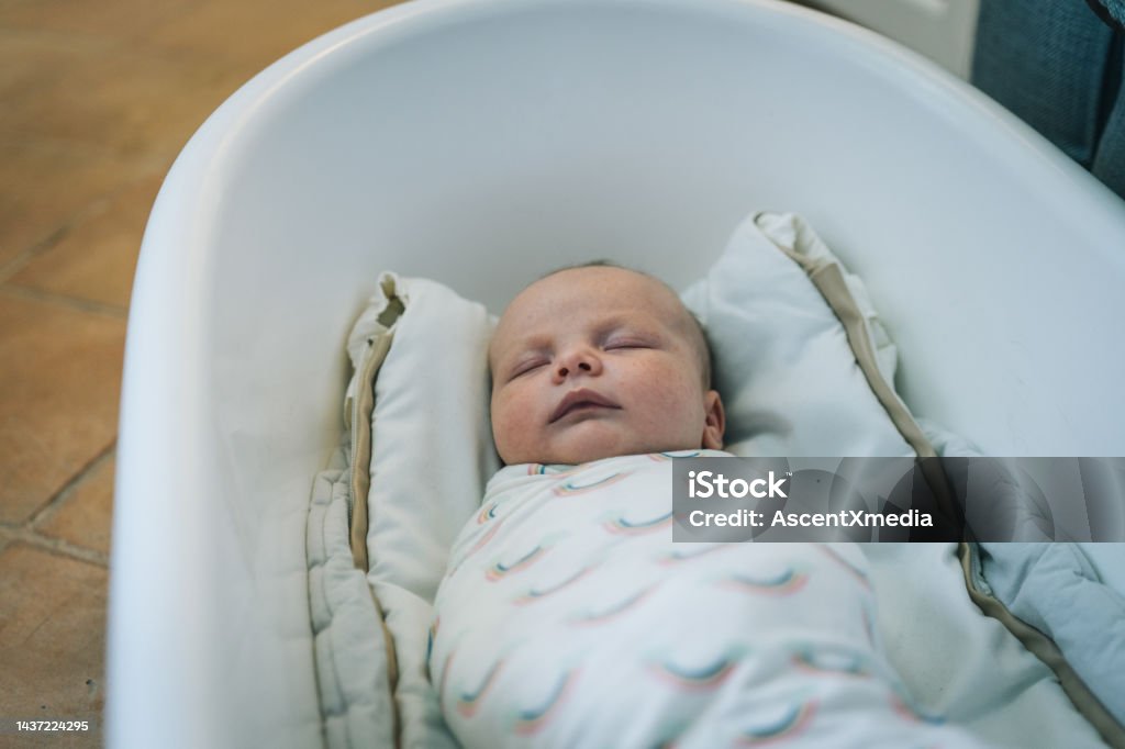 Infant girl sleeps in baby bathtub She is swaddled in blanket 0-1 Months Stock Photo