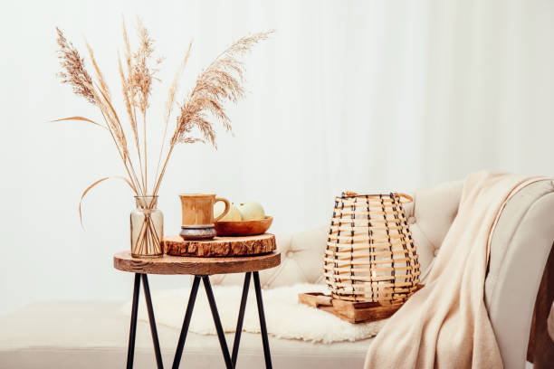 istock Cozycore or cottagecore concept, warm soft brown beige interior design objects. Cozy wool plaid on sofa, candle burning in wood lantern, tea cup on wood table. Warm color photo manipulation. 1437226739