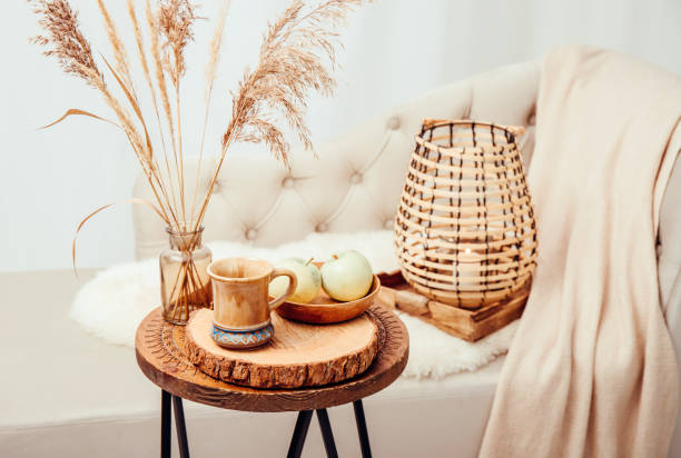 Cozycore or cottagecore concept, warm soft brown beige interior design objects. Cozy wool plaid on sofa, candle burning in wood lantern, tea cup on wood table. Warm color photo manipulation. concepto cozycore o cottagecore, cálidos objetos de diseño de interiores de color beige marrón suave. acogedora lana a cuadros en el sofá, vela encendida en linterna de madera, taza de té en mesa de madera. manipulación de fotos en color cálido.