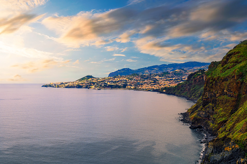 Sunset over capital city of Funchal and cliffs and mountains of Madeira Island, Portugal