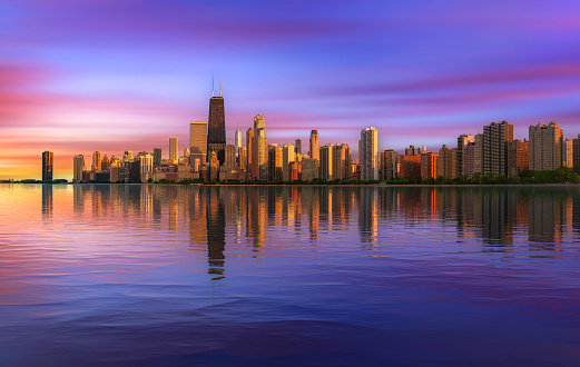 Colorful sunset above Chicago skyline across Lake Michigan with reflection in water.