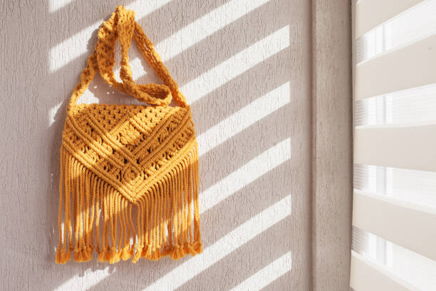 Handmade macrame cotton ross-body bag. Eco bag for women from cotton rope. Scandinavian style bag.  Yellow color, sustainable fashion accessories. Details. Close up image stock photo