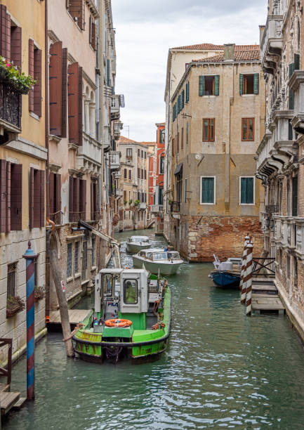 Venice, Italy - October 10th 2022:  Boat with a crane removing construction garbage in narrow canal in the center of the old and famous Italian city Venice