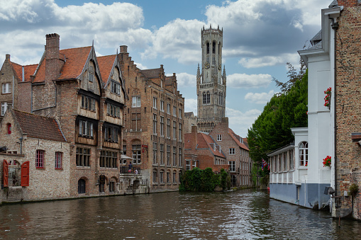 A view from the old historical and touristic city of Bruges in Belgium, Church of Our Lady from the canal and historical houses in summer.