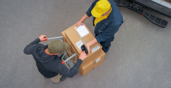 Overhead view of delivery person taking signature from customer after delivering the packages.