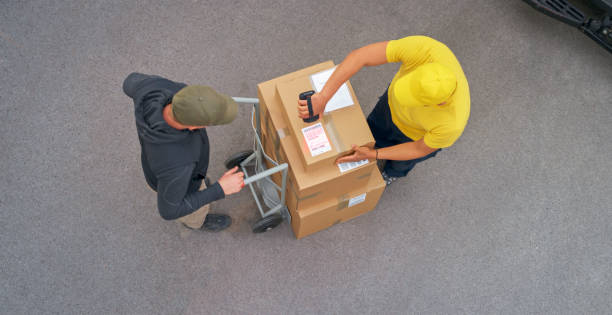 delivery person scanning packages - polo shirt two people men working imagens e fotografias de stock