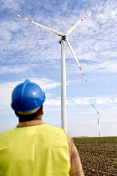 istock Rear view of engineer looking at wind turbine on the field 1437232813