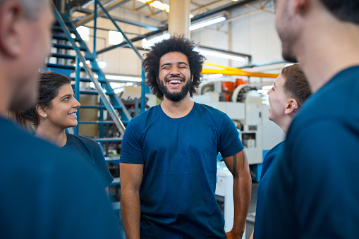 Cheerful young male engineer with multiracial colleagues in industry