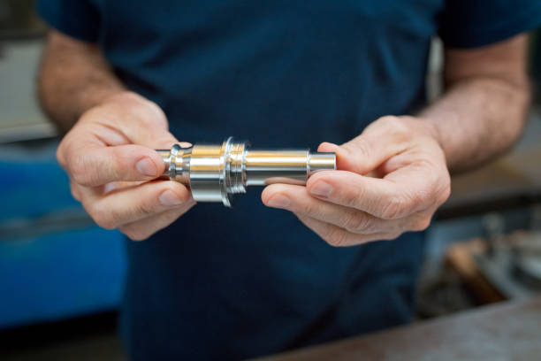 istock Midsection of male engineer holding machine part in industry 1437234189