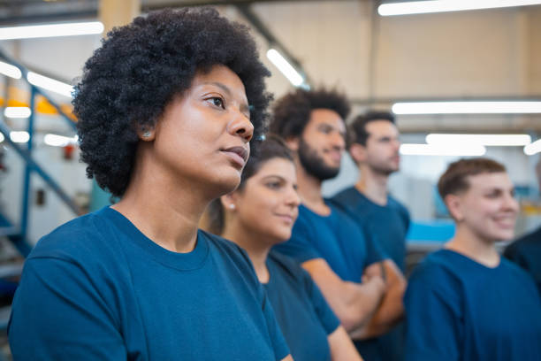 istock Thoughtful female engineer looking away while standing by colleagues in industry 1437235623