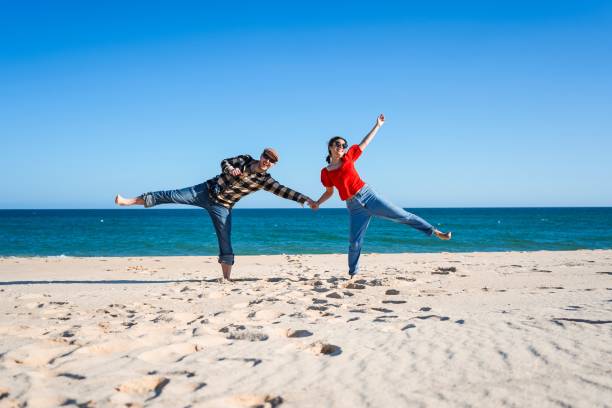 istock Tourist couple standing on wide open white beach under blue sky 1437236856