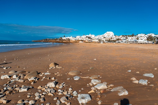 Beach Town with white buildings, sandy beach with rocks along the ocean
