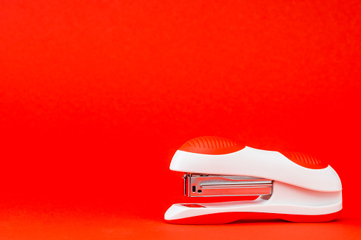 White stapler on red background