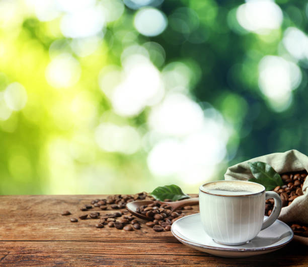istock Cup of aromatic hot coffee and beans on wooden table outdoors. Space for text 1437238628