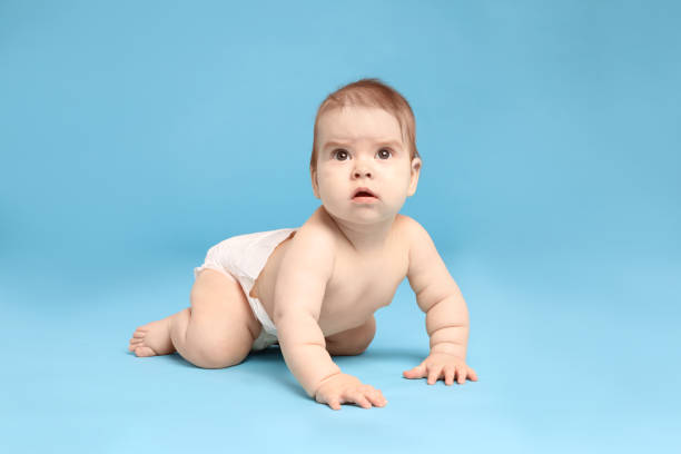 istock Cute little baby in diaper crawling on light blue background 1437239089