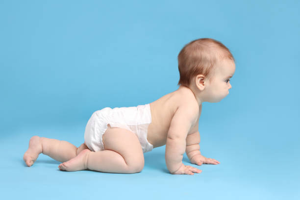 istock Cute little baby in diaper crawling on light blue background 1437239184