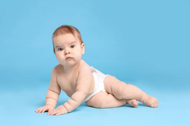 istock Cute little baby in diaper on light blue background 1437239535