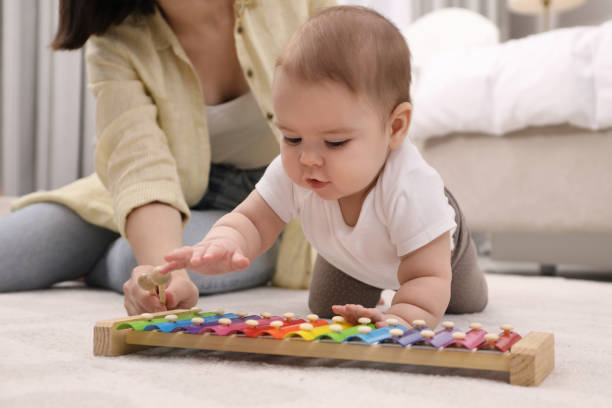 mignon bébé et mère jouant avec du xylophone sur le sol à la maison - female nurse photos et images de collection