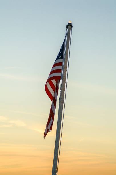 istock Vertical shot of American flag hanging from flag pole during sunset 1437243009
