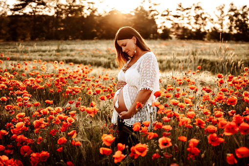 A pregnant model posing for a photoshoot in a field.