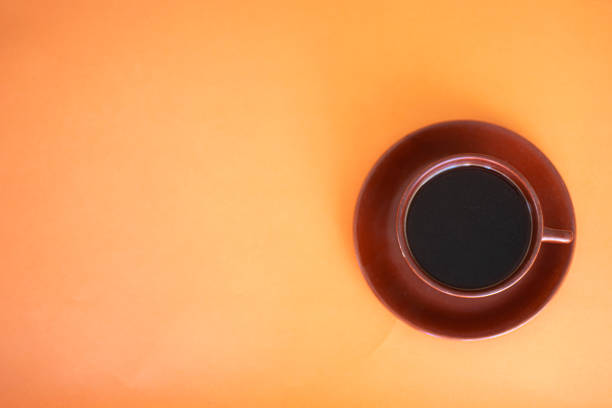 istock cup of coffee brown cup and orange background 1437246055