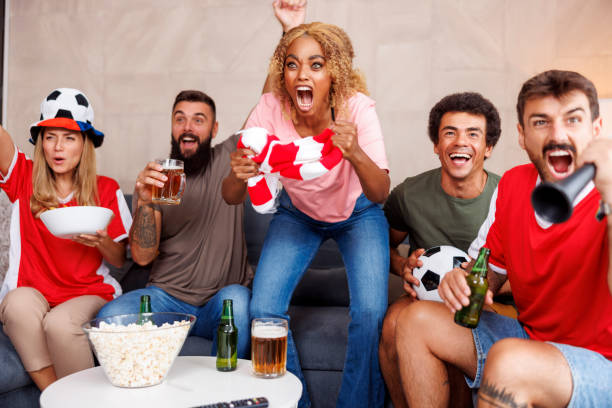 istock Friends having fun cheering while watching football on TV 1437246424