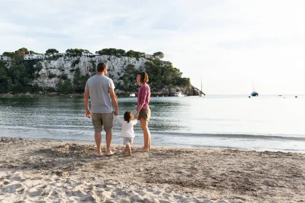 Photo of Happy family having a walk in a nice sand beach called cala Galdana located in Minorca, spain.