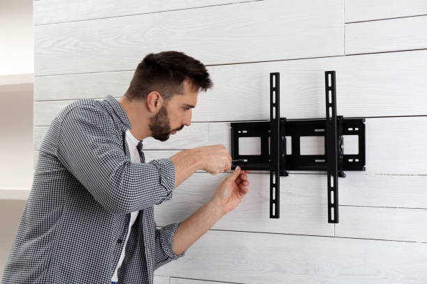 Man with screwdriver installing TV bracket on wall indoors Man with screwdriver installing TV bracket on wall indoors installing tv stock pictures, royalty-free photos & images