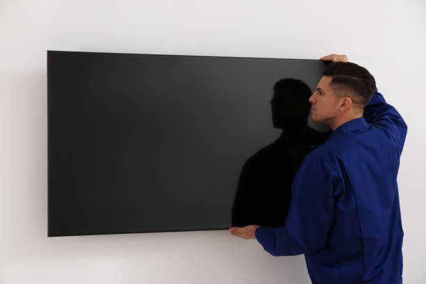 Professional technician installing modern flat screen TV on wall indoors Professional technician installing modern flat screen TV on wall indoors installing tv stock pictures, royalty-free photos & images