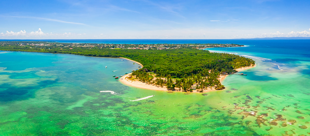 An aerial panoramic view of tropical island beautifully covered with lush trees under a clear sky