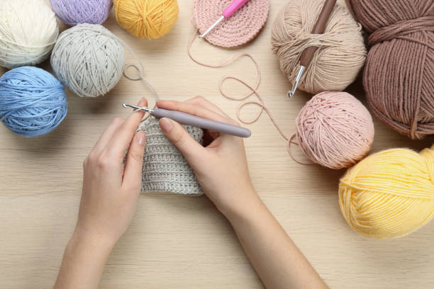 istock Woman crocheting with grey thread at wooden table, top view 1437250556