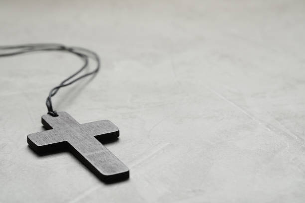 istock Wooden Christian cross on light grey table, closeup. Space for text 1437250599