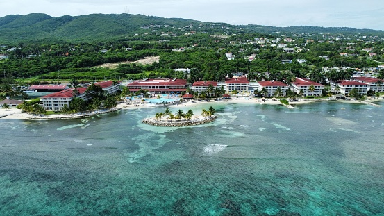 An aerial of hotels on a beach covered with greenery against a turquoise sea in Montego Bay, Jamaica