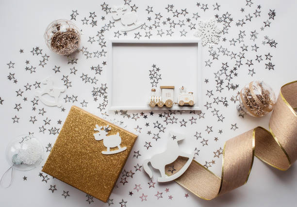 istock Christmas frame with white and gold decorations, gift box and train on a white background. Flat layout, top view, place to copy. The concept of the new year 2023 1437251530