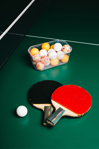 Studio shot of two ping pong rackets and a ball are on the green game table