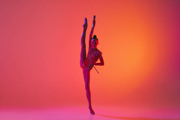 istock Beautiful and flexible graceful athlete rhythmic gymnastic artist dancing, doing stretch exercises isolated on colorful background in neon. Beauty, art, sport 1437252652