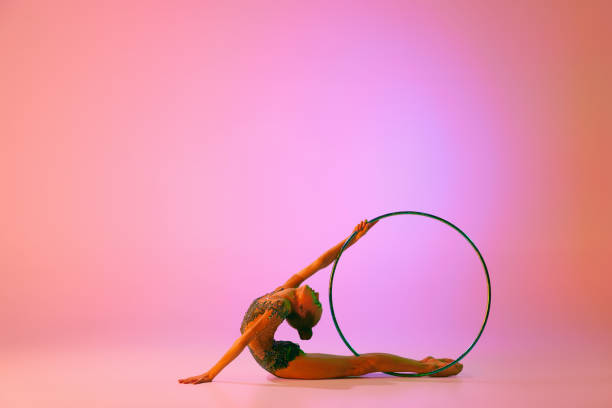 istock Beautiful and flexible graceful athlete rhythmic gymnastic artist dancing, doing stretch exercises isolated on colorful background in neon. Beauty, art, sport 1437252679