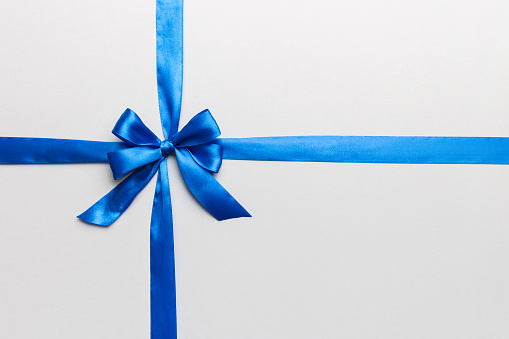 Blue giftbox with white ribbon on blue background.