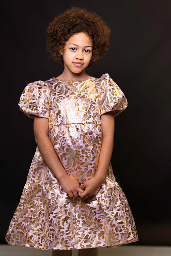 Little girl in a dress stands in a room near an inflatable golden figure. High quality photo
