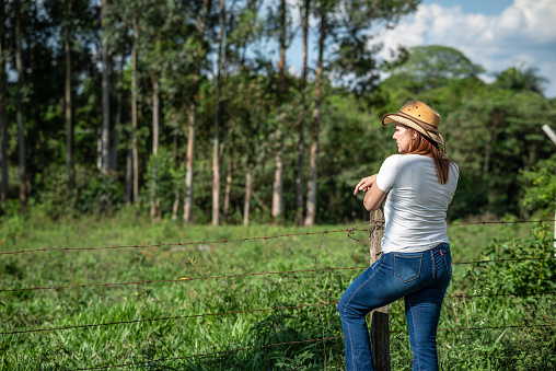 Portrait of a mature woman in a ranch, enjoying her time there in a beautiful and calm environment, surrounded by nature and trees.