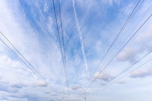 Poles and wires of power supply system of EMUs under blue sky and white clouds