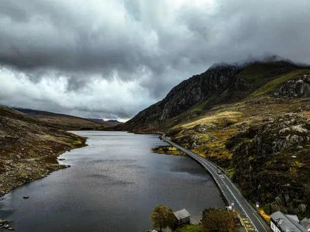 Aerial photograph of Llyn Ogwen with the popular travel route of the A55 road running by the side of Tryfan Mountain, Bangor, Nant Ffrancon, Wales. Contrasty photograph with dramatic clouds