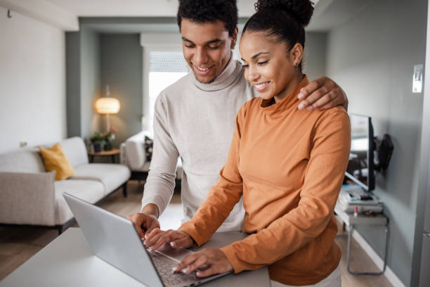 istock Young couple smiling and looking at the laptop 1437262912