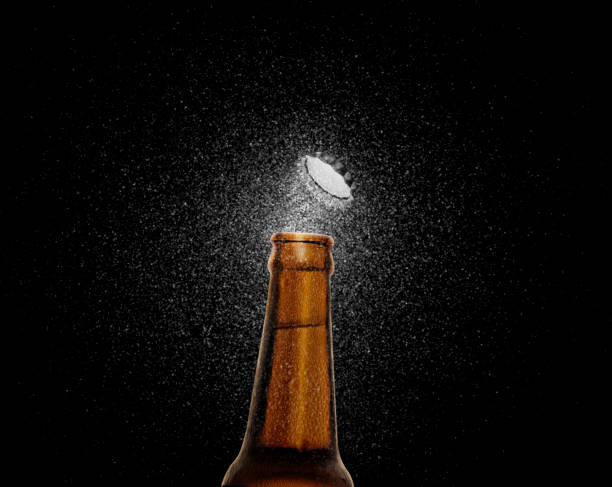 closeup photo of an amber beer bottle splashing beer drops on a black background. beer cap flying on top of the bottle. 3d render - amber beer imagens e fotografias de stock