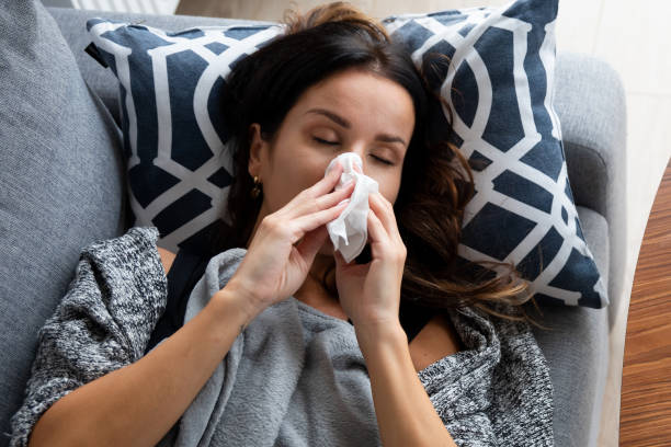 istock Sick woman blows her nose, lying on bed 1437265289