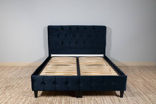 istock Bed with blue fabric upholstery and a wooden frame without mattress in an empty room 1437269465